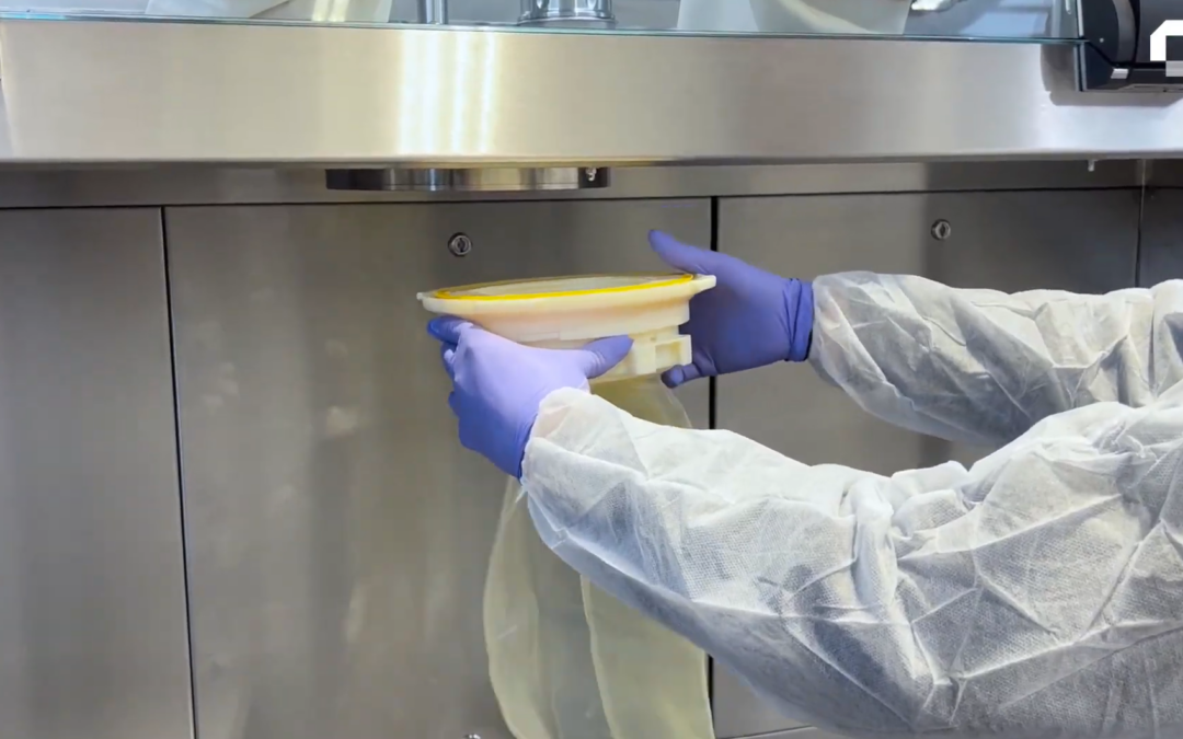 Simplifiez la gestion de vos déchets en environnements stériles 2 Opérateur manipulant un sac souple de transfert sous isolateur pharmaceutique dans un environnement de confinement