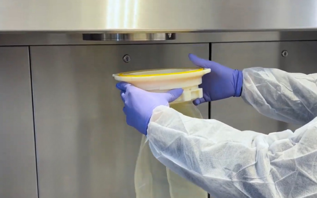 Simplifiez la gestion de vos déchets en environnements stériles 2 Opérateur manipulant un sac souple de transfert sous isolateur pharmaceutique dans un environnement de confinement